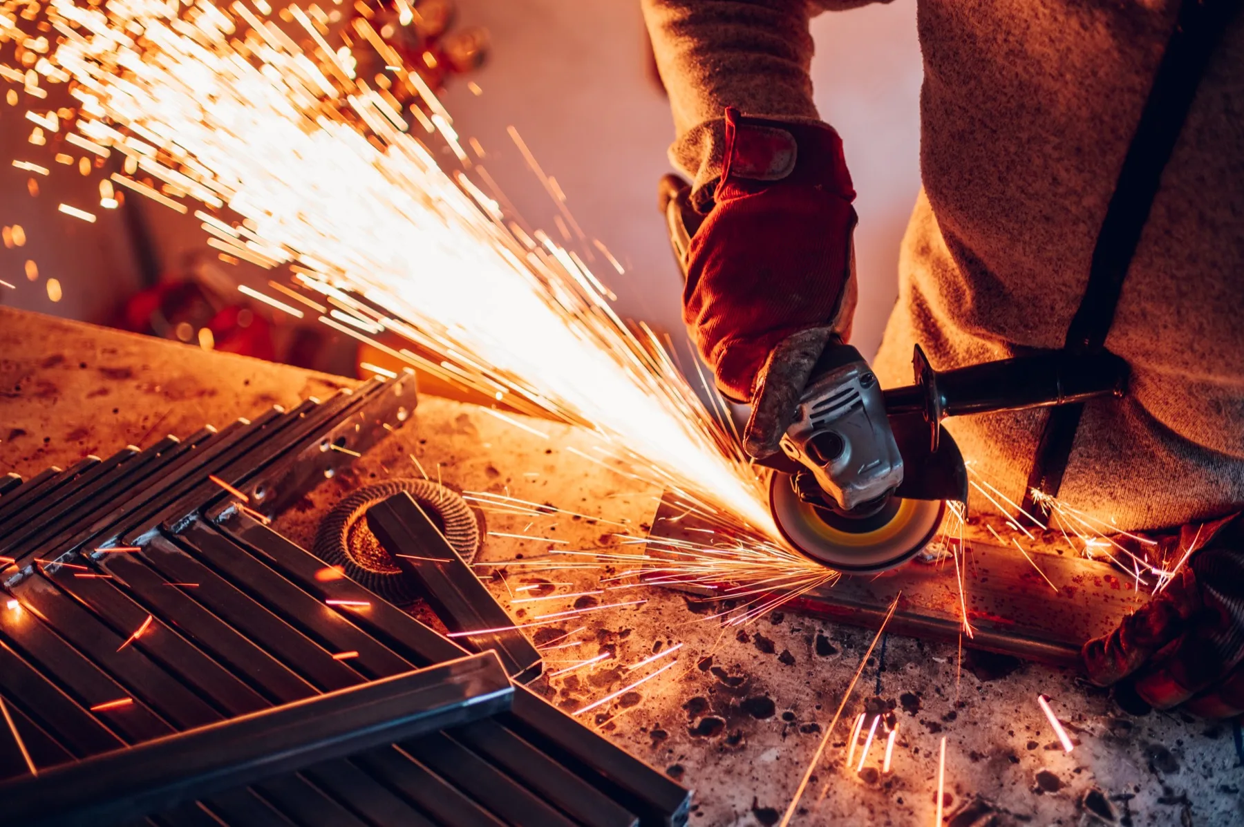Metallschleifer bei der Arbeit mit Winkelschleifer und Funkenflug in der Lohnschleiferei Prestipino